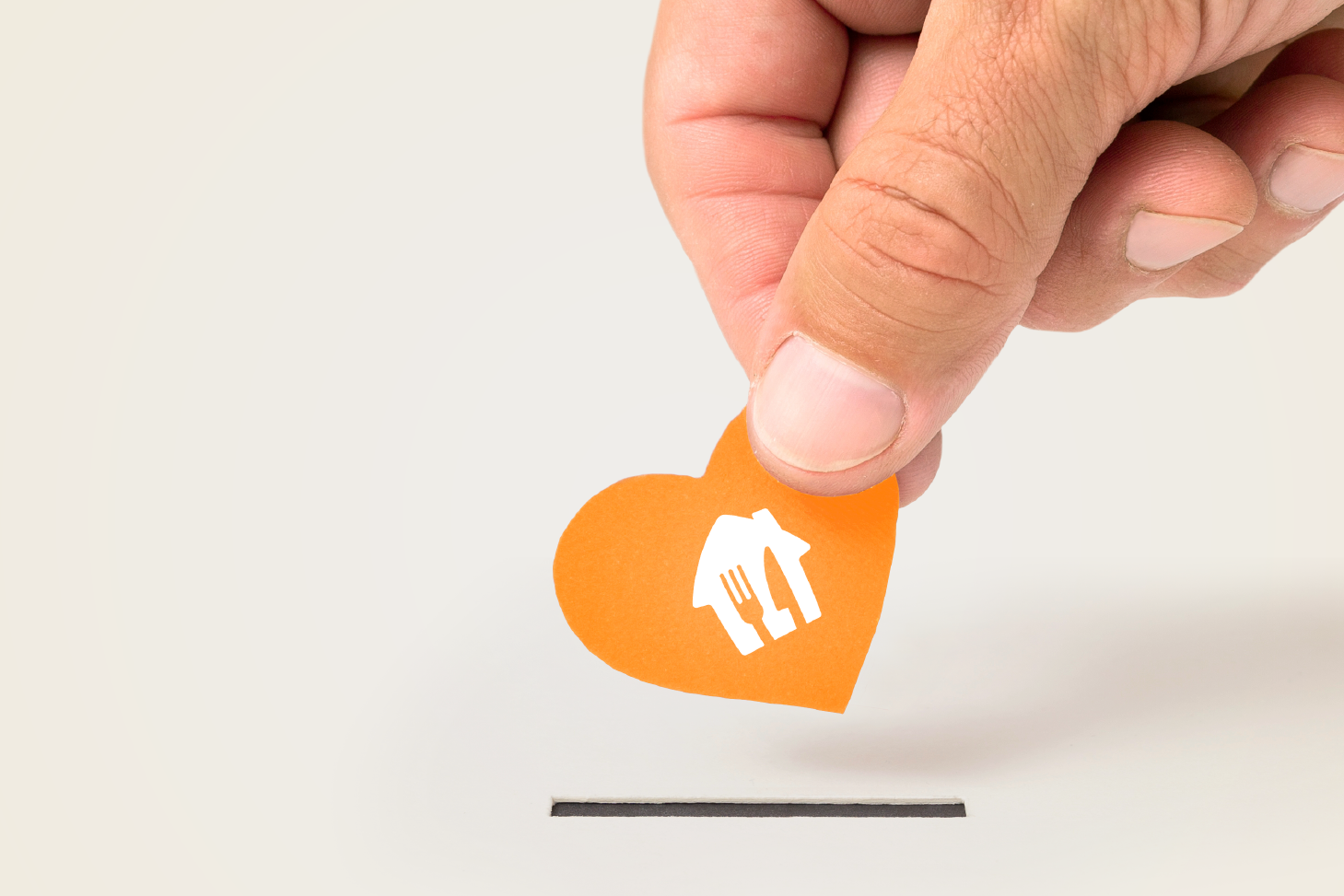 Fingers holding orange heart with Skip Logo