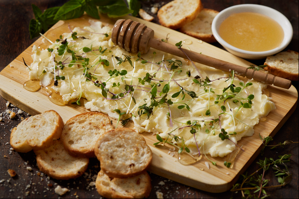 Butter with garnish spread on a cutting board beside crackers.
