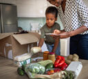 Mother and son unboxing their grocery home delivery order in the kitchen.