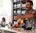 Bartender stirring up a drink while engaging and laughing with customers.