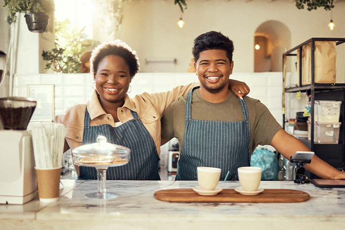 Two happy café workers smiling at the camera.