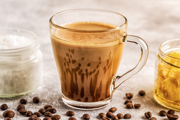 A clear glass coffee mug filled with hot Olive Oil coffee.